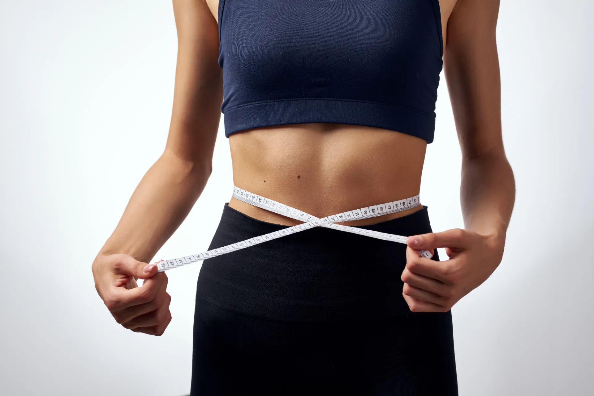woman measures her waist with measuring tape utc